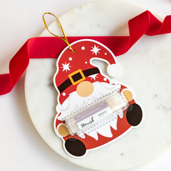 Gnome-shaped product packaging with a red ribbon on a white surface