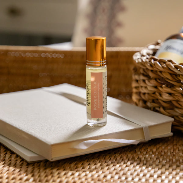 Power of She Roller Blend on a stack of books with a blurred background