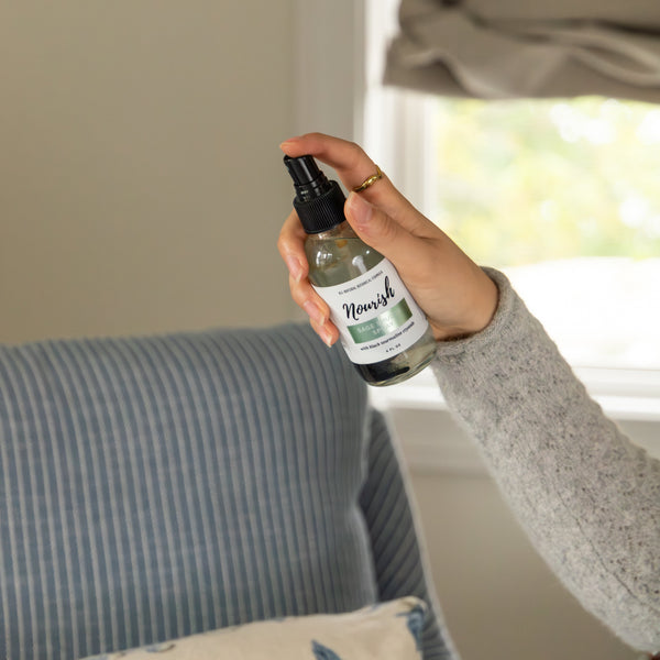 Person holding a bottle of Sage Smudge Spray in a home setting
