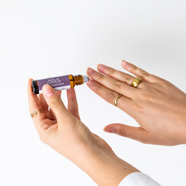 Person applying Nail & Cuticle Blend to their nails on a white background
