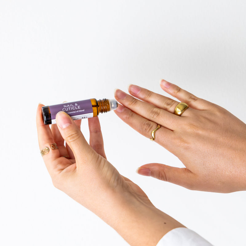 Person applying Nail & Cuticle Blend to their nails on a white background