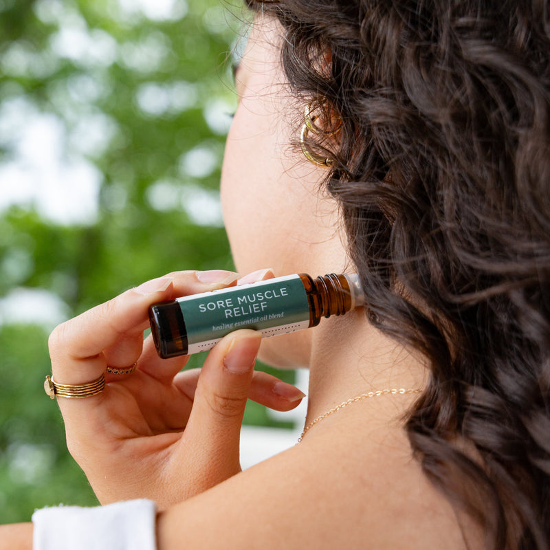 Woman applying Sore Muscle Relief Blend to the back of her neck outside