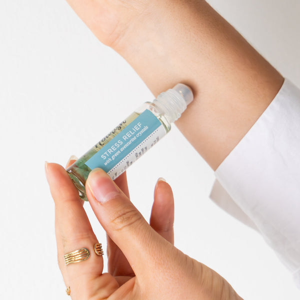 Person applying Stress Relief Roller Blend to their wrist with a white background