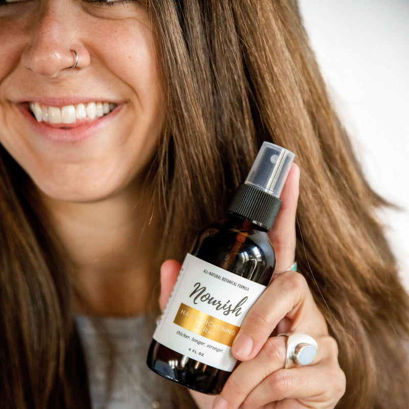 Woman holding a bottle of Hair Thickening Spray