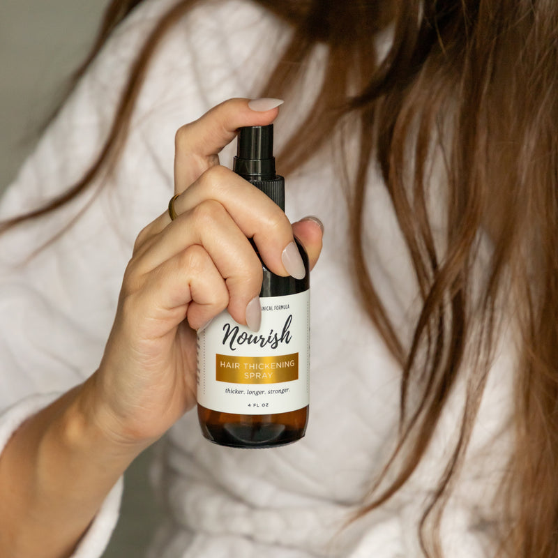 Woman holding Hair Thickening Spray by hair