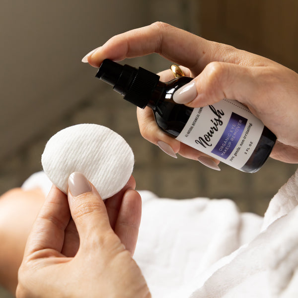 Person holding Eye Makeup Remover and cotton pad in a bathroom setting
