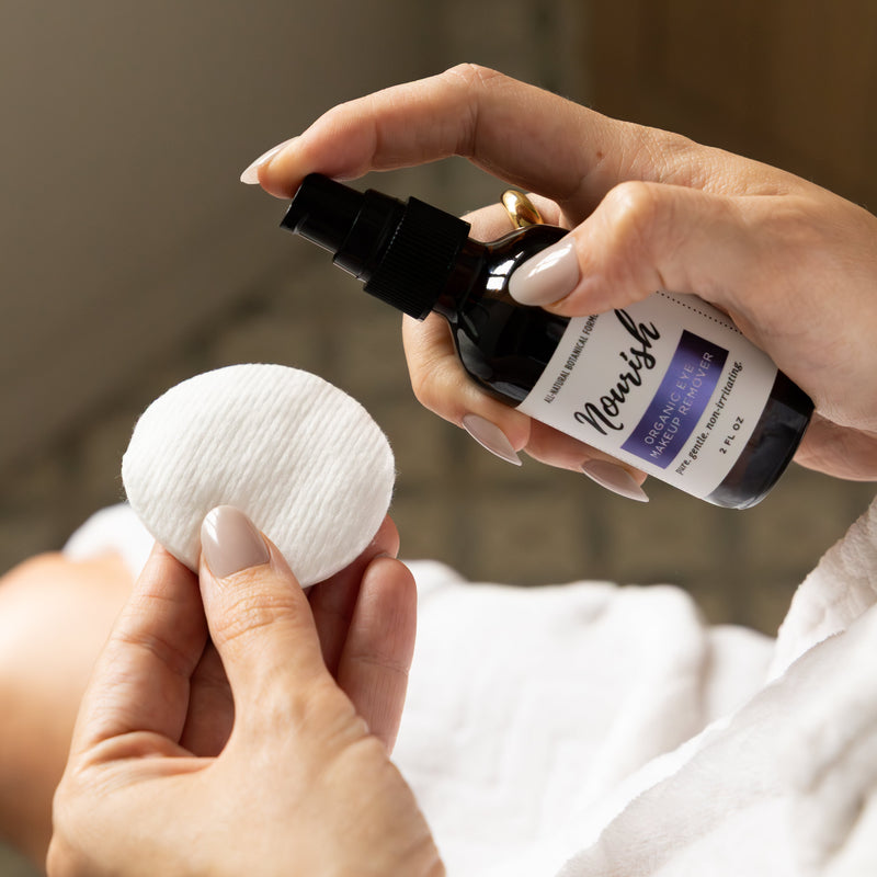 Person holding Eye Makeup Remover and cotton pad in a bathroom setting